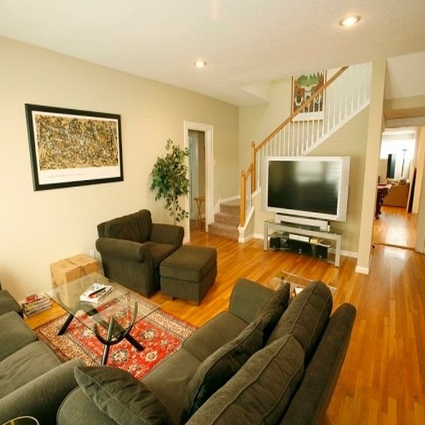 Indoor photo of living room in sober living home with staircase, hardwood floors, flat panel television and nice furniture