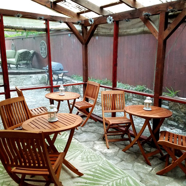 Picture of enclosed patio with teak wood furniture and barbeque pit outside