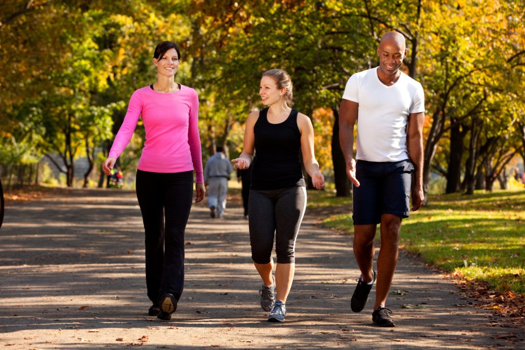 Outdoor photo of two ladies and a gentleman walking through Zilker park on a warm sunny day