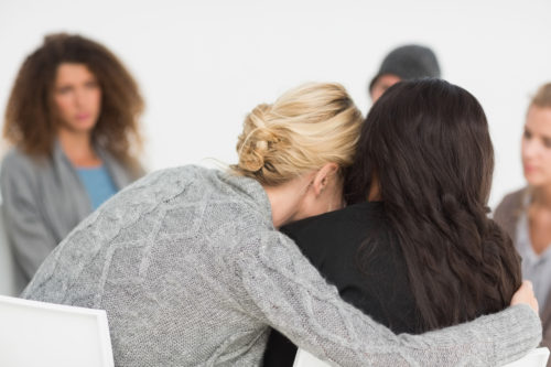 Photo of clients hugging during a therapy class, structured sober living